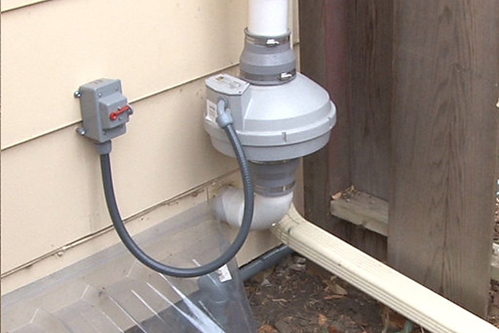 Exterior radon mitigation fan and vent pipe installed at a Pennington County home